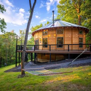 a log house with a hammock in front of it at Shenandoah Yurt: Hot Tub~Wood Stove~WiFi~EVcharger in Stanley