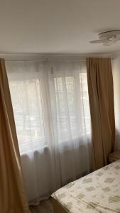 a bedroom with white curtains and a window at Private Room in city centre KM0 in Bucharest +3 photos