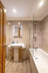 a bathroom with a sink and a shower and a tub at Gwithian Holidays in Hayle