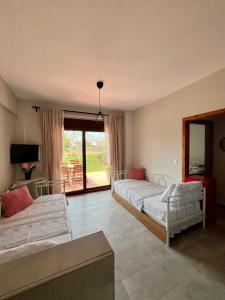 a bedroom with two beds and a television and a balcony at Lucid Dream Apt. Bozinis 2 in Psakoudia