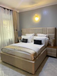 een slaapkamer met een groot bed met witte lakens en kussens bij 8693 Abba Place in Kampala