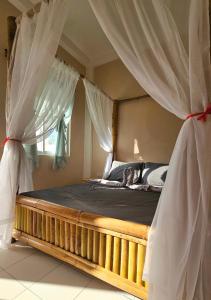 een slaapkamer met een hemelbed en gordijnen bij Mangoverde Guesthouse in Moalboal