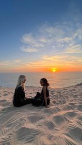 dos mujeres sentadas en la playa viendo la puesta de sol en Olympe Surf & Yoga en Tamraght Ouzdar