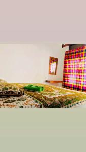 een slaapkamer met een bed met een groen dekbed bij Sanity Door Rooms and Hostel in Arugam Bay