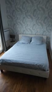a bed in a bedroom with a blue wall at Au Bois Fleuri in Bracieux