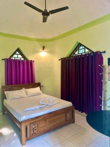 a bedroom with a bed with purple curtains at Rams Gratitude Inn in Varkala