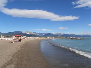 a beach with people sitting on the sand and the water at Villa Vecchia Fontana al mare - Tra Liguria e Toscana tra Viaregggio, Forte dei Marmi e Cinque Terre- Haus am Meer bei la Spezia in Bocca di Magra