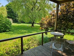 a table and chair on a porch with a view of a park at Le Clos du Clocher in Gueudecourt