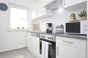cocina blanca con microondas y fogones en RT03-FW Wohnung in Schwanstetten, en Schwanstetten
