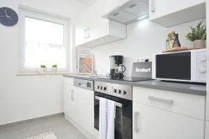 a white kitchen with a microwave and a stove at RT03-FW Wohnung in Schwanstetten in Schwanstetten