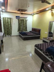 a room with two beds and a couch in it at Mahakal Homestay in Ujjain
