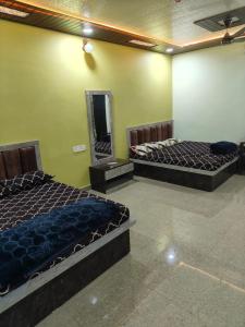 two beds in a room with a mirror at Mahakal Homestay in Ujjain