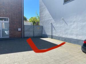 un objeto rojo sentado a un lado de un edificio en Privates & gemütliches Appartement inklusive Parkplatz, en Drensteinfurt