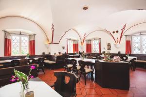 una sala da pranzo con tavoli, sedie e finestre di Schlossgasthof Rösch a Blaibach