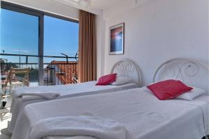 Cette chambre comprend 2 lits avec des oreillers rouges et un balcon. dans l'établissement CARETTA PANSİYOn, à Kaş