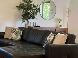 a black leather couch in a living room with a mirror at Humble & Homely in Rockingham