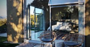 a bedroom with a bed and two chairs on a patio at The Hidden Spring in Wanaka