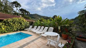 a group of white chairs next to a swimming pool at Casa Mara in Nova Friburgo