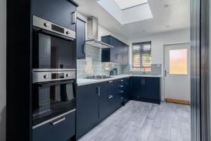 a large kitchen with blue cabinets and a skylight at Gorgeous Loft Room in Beckenham