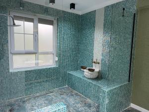 a green tiled bathroom with a shower and a window at İstanbul Airport Treekos Suite Hotel in Karaburun