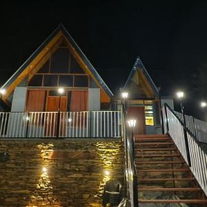 ein Haus mit einer Treppe und Lichtern in der Nacht in der Unterkunft Snowind Cottages in Kūfrī
