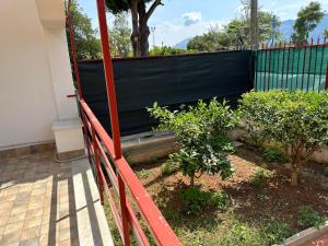 uma cerca vermelha ao lado de um jardim com árvores em Mondello Sabrina Apartments em Mondello