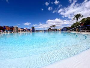 a large swimming pool with blue water and palm trees at Holiday home in meloneras with sea views, golf and private jacuzzi in Maspalomas
