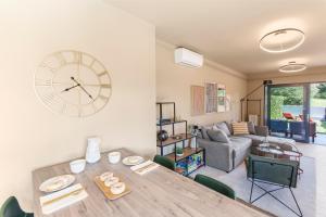 un soggiorno con un tavolo e un orologio a parete di NEW stylish Casa Melisa with 2 gardens and BBQ facilities! a Poreč (Parenzo)