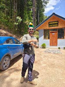 Un uomo è in piedi di fronte a un edificio di Snowind Cottages a Kūfrī