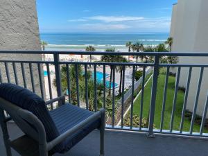 a chair on a balcony with a view of the ocean at Pelican Condominium in New Smyrna Beach