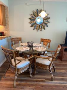 a dining room table with four chairs and a mirror at Pelican Condominium in New Smyrna Beach