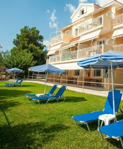 a group of beach chairs and umbrellas in front of a building at Rosa's Beach Studios in Lourdata