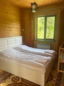 ein großes Bett in einem Holzzimmer mit Fenster in der Unterkunft Prince Guest House in Dilidschan