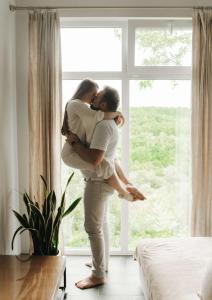 a man and woman kissing in front of a window at Сottage "Family Estate" in Kamianets-Podilskyi