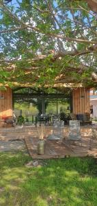 un patio avec des chaises et des tables sous une pergola dans l'établissement Adorable lodge en bord de forêt, proche lac 800m, à Sanguinet