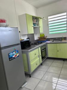 a kitchen with green cabinets and a refrigerator at Maison tartanaise in La Trinité