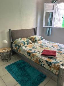 ein Bett in einem Schlafzimmer mit zwei Teppichen darauf in der Unterkunft Maison tartanaise in La Trinité