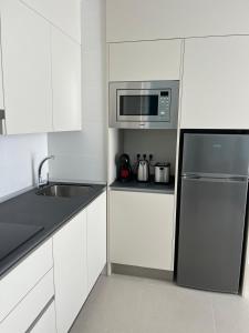 a white kitchen with a refrigerator and a microwave at Albatros Apartments by Malibu in Callao Salvaje