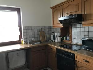 a kitchen with wooden cabinets and a black stove top oven at Ferienwohnung Landidylle in Friedrichshausen +8 photos