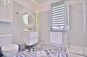 une salle de bain blanche avec toilettes et douche dans l'établissement Sunset Apartments - Monte Cassino 6 - przestronny apartament przy deptaku, à Świnoujście 9 autres photos