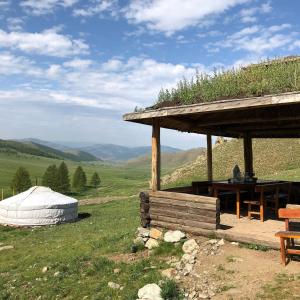Dream Adventure Mongolia في Nalayh: شرفة مع سقف من العشب على تلة