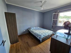 a bedroom with a bed and a desk and a window at Apartamento bem localizado. in Caraguatatuba