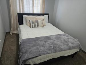 een groot bed met kussens en een grijze deken bij 3 bedroom Town in Stonebridge unit 303 in Saskatoon