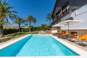 a swimming pool with chairs and umbrellas next to a house at Casa El Maizal in Marbella