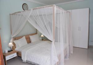 a bedroom with a canopy bed with white curtains at Chez Ouly in Dakar