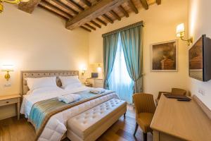 - une chambre avec un grand lit et un bureau dans l'établissement Relais Paradiso Resort & Spa, à Gualdo Cattaneo