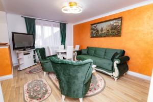 a living room with a green couch and chairs at Casa de pe colt in Alba Iulia