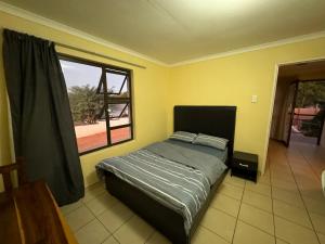 um quarto com uma cama e uma grande janela em Ramblers Self-Catering Hostel (No Aircon/No TV/No Pool) em Windhoek