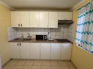 una pequeña cocina con armarios blancos y microondas en Ramblers Self-Catering Hostel (No Aircon/No TV/No Pool), en Windhoek
