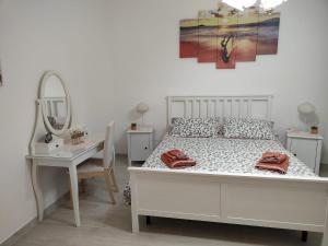 a bedroom with a white bed with a mirror and a table at Holiday house Chiara in Giardini Naxos